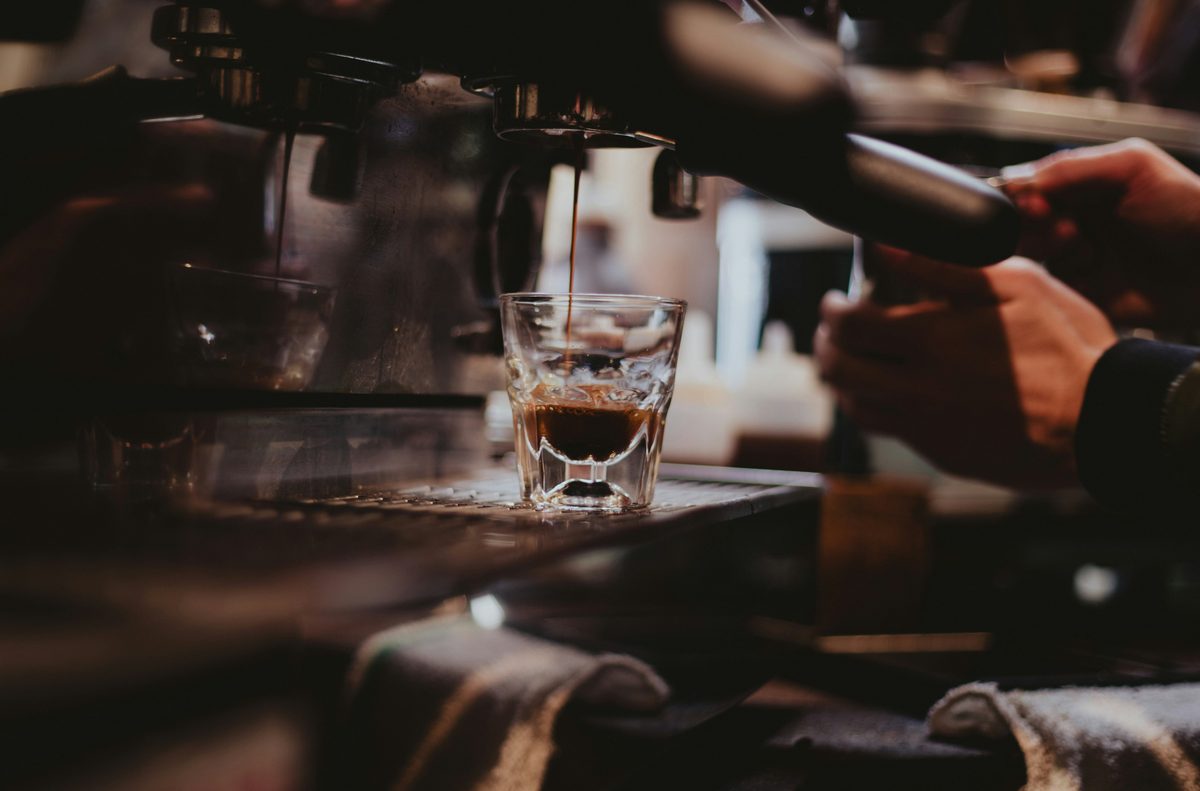 Espresso pulling into a glass on a warm-lit bar